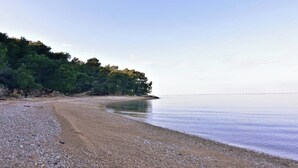 A pebbly beach with a forested area on the left and calm water. - Charming vacation home with garden (Umag)