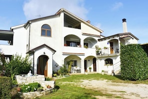 Ein zweistöckiges Haus mit Terrasse, Steintreppe und einem gepflegten Garten.