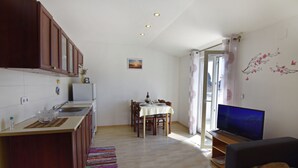 Un espacio habitable compacto con kitchenette, comedor y televisor.