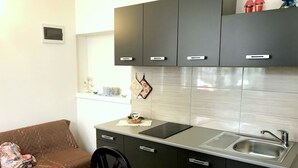 Uma cozinha compacta com pia, armários e área de refeições com mesa e cadeiras.