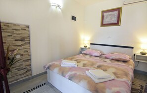 A bedroom with a bed, bedside lamps, a wall-mounted picture, and a decorative wall panel. - Compact studio stay with sea views and BBQ (Zambratija)