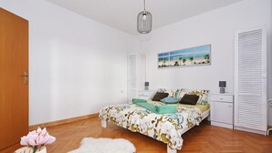 Ein Schlafzimmer mit Bett, Nachttisch, Lampe, Gemälde und Kleiderschrank.