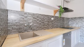 Eine Küche mit Steinrückwand, Arbeitsplatte aus Holz, Spüle aus Edelstahl und einem Geschirrspüler.