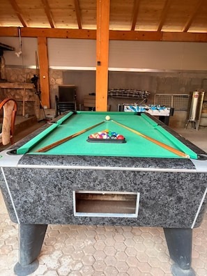 Ein Billardtisch mit grüner Spielvliesdecke, umgeben von sechseckigen Fliesen.