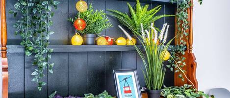 Una estantería de madera con plantas en macetas, esferas decorativas y un cuadro enmarcado.