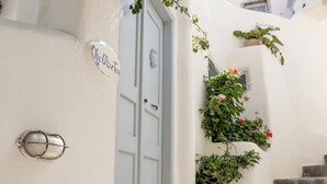 A white door with a sign reading 'The Oliver Tree,' a small potted plant, and a staircase leading up. - Thera Bliss "Olive Tree" Suite Private Pool by ΜΡS (santorini)