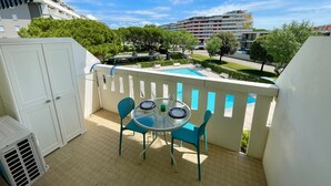 Een balkon met een pooltafel, stoelen en uitzicht op een woonwijk.
