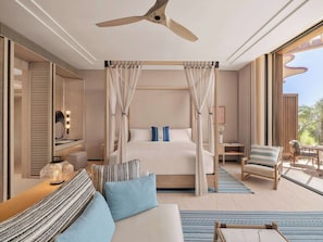 A modern hotel room with a bed, a sitting area, a desk, and a balcony.