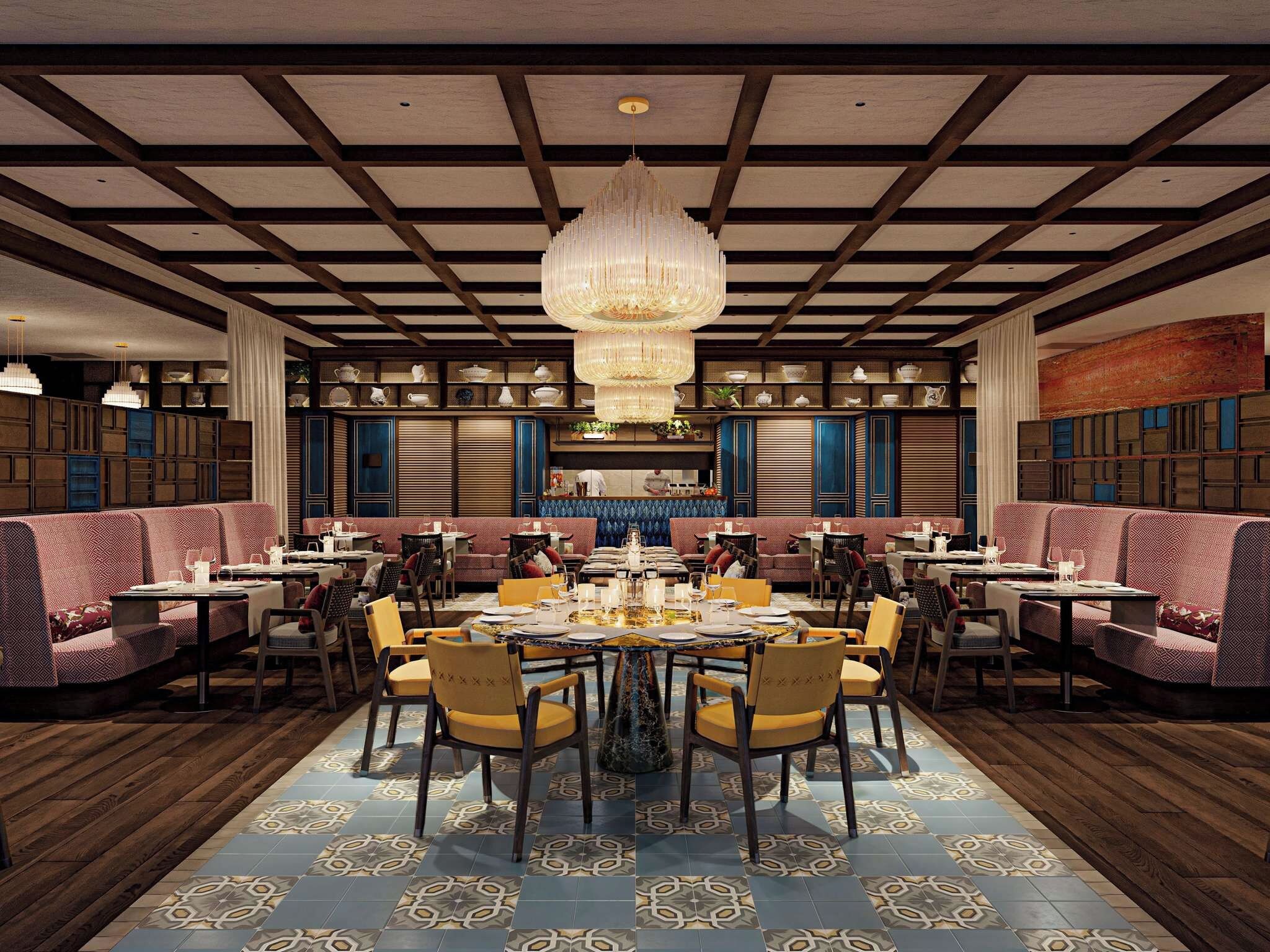 A restaurant with a central round table, multiple seating areas, and a decorative chandelier.