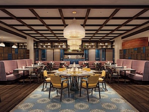 A restaurant with a central round table, multiple seating areas, and a decorative chandelier. - Raffles The Red Sea (Umluj)