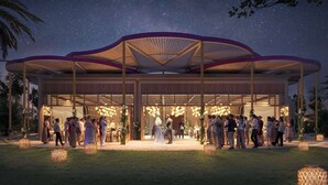 Un espacio para eventos techado al aire libre, con una zona central abierta, rodeado de arreglos de asientos e iluminación decorativa.