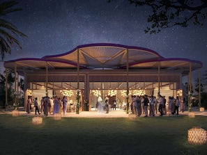 A covered outdoor event space with a central open area, surrounded by seating arrangements and decorative lighting.
