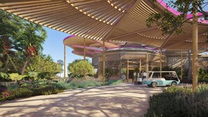 Un espacio al aire libre techado con una estructura de madera curva, un camino y un coche antiguo estacionado bajo la marquesina.