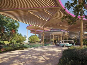 A covered outdoor area with a curved wooden structure, a pathway, and a vintage car parked under the canopy.