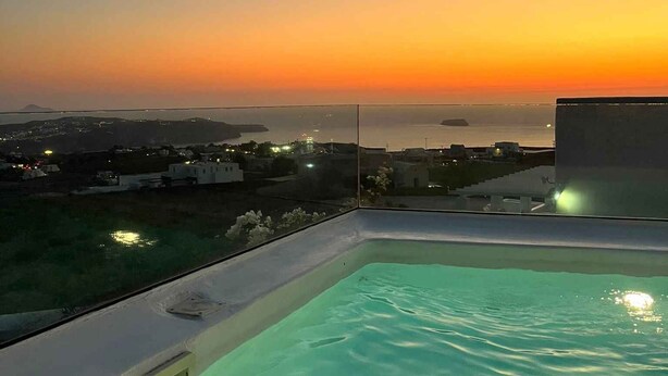 Ein Pool auf dem Dach mit Blick auf einen Sonnenuntergang über einer Küstenstadt.