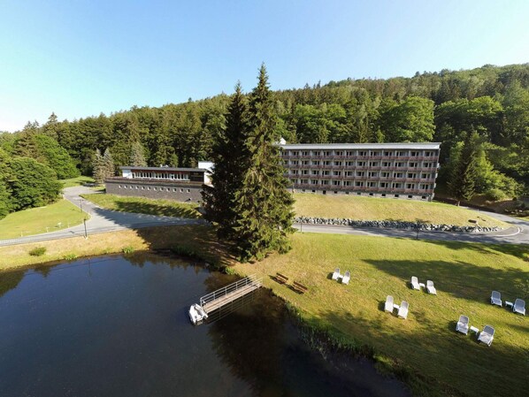 A large building with multiple balconies, a parking area, and a body of water with a dock. - 2 Person Holiday Park Home in Erlbach (Markneukirchen)
