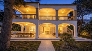 A two-story building with a covered patio, outdoor seating, and a staircase leading to the upper level. - Spacious 5-bedroom en-suite villa with pool in stunning Playa de Muro with AC (Muro)