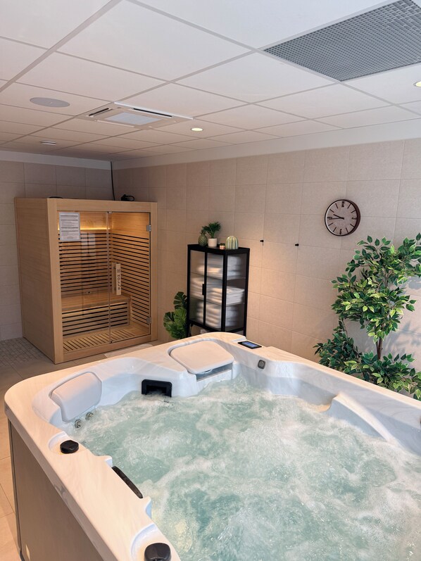 A spa area with a hot tub, a wooden cabinet, a clock, and a potted plant.