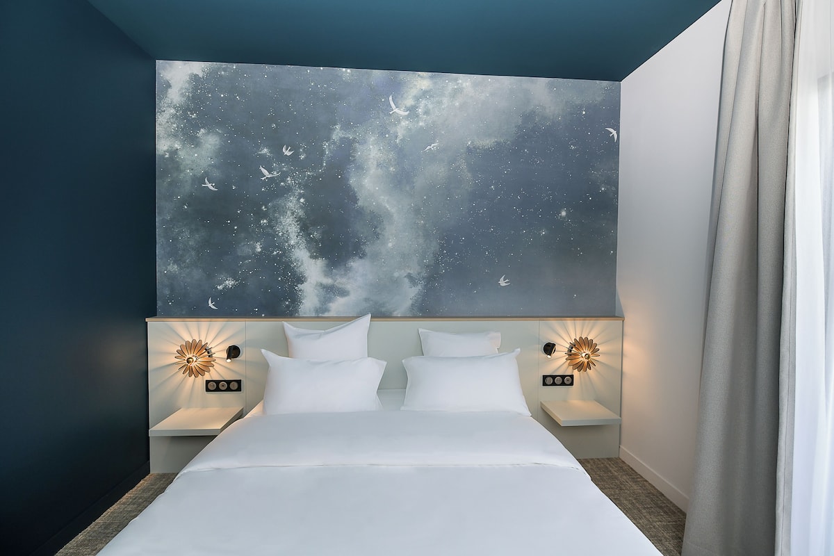 Ein Schlafzimmer mit einem Bett, zwei Nachttischen und einem Wandbild.