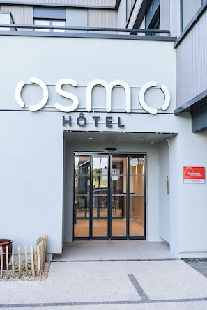 A hotel entrance with a modern design, featuring a glass door and a sign above that reads 'OSMO HOTEL'. - The Originals Boutique Osmo Hôtel (Chantepie)