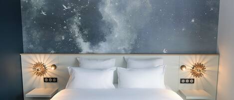 A bedroom with a bed, two nightstands, a wall-mounted light fixture, and a large wall art depicting a night sky with birds.