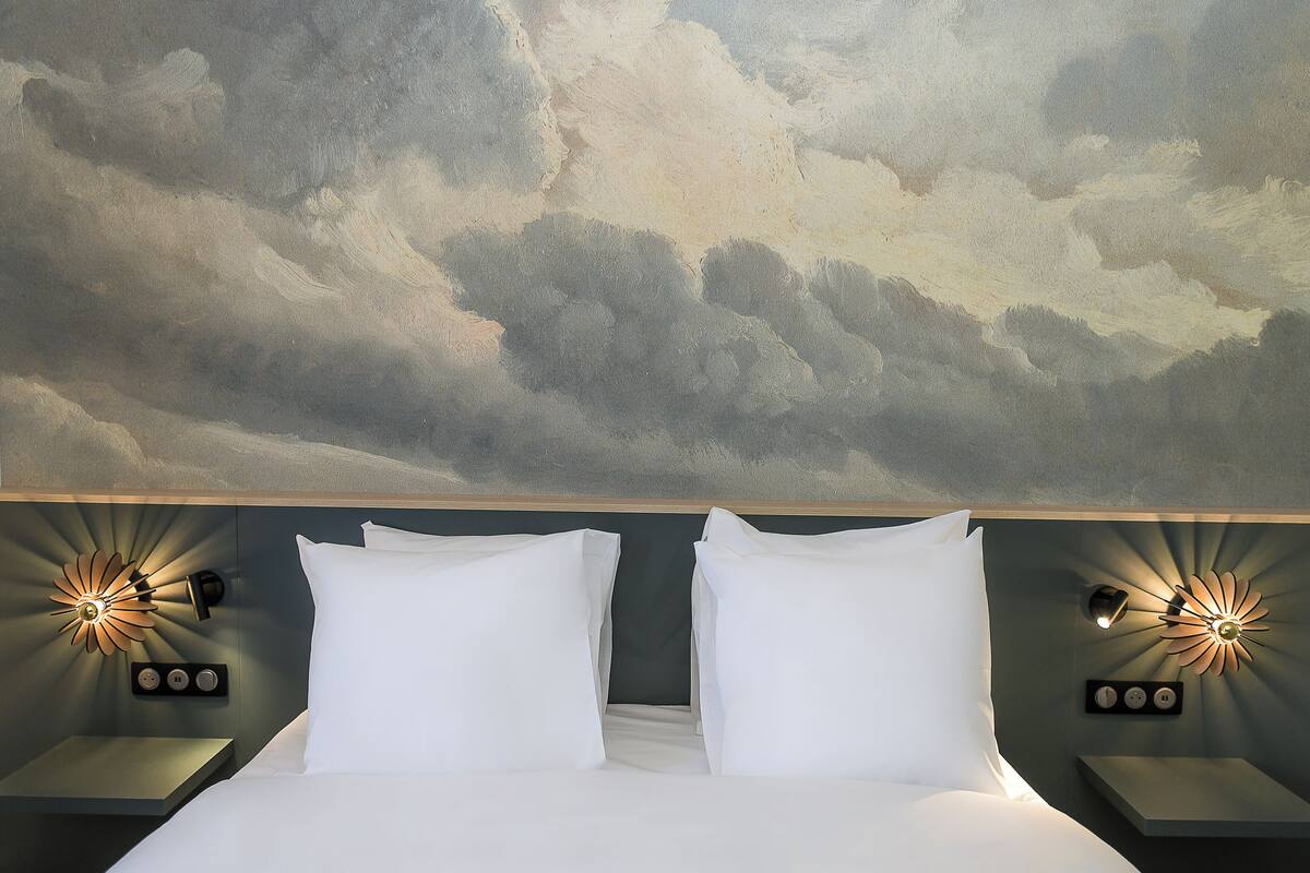 Ein Hotelzimmer mit Bett, zwei Nachttischen und Wandleuchten.