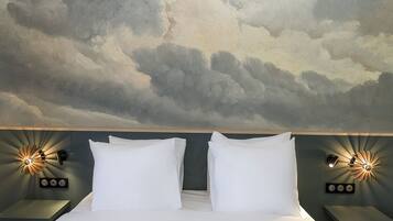 Una habitación de hotel con una cama, dos mesitas de noche e iluminación en la pared.