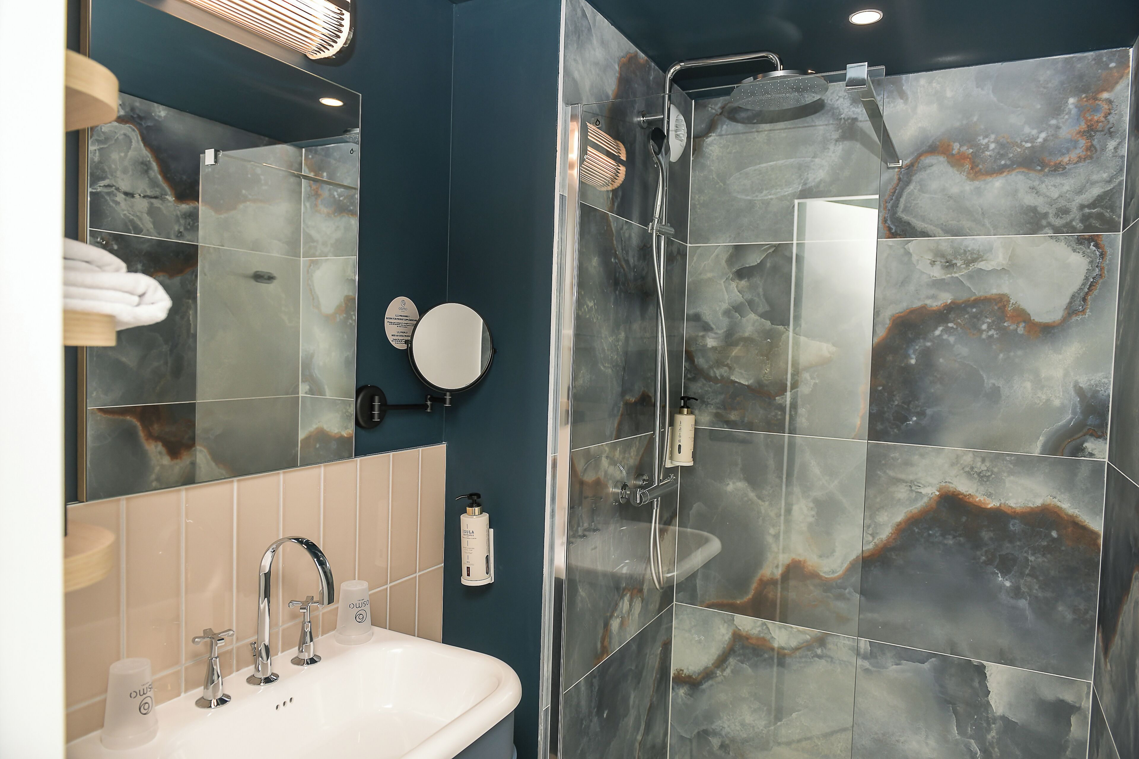 Une salle de bain avec un lavabo, un miroir et une douche.