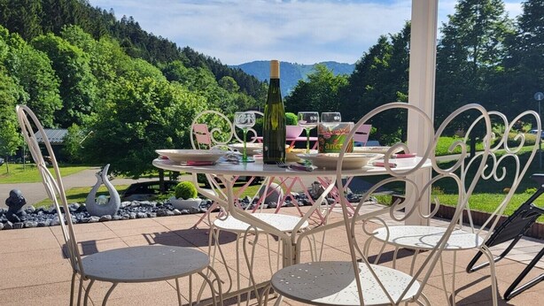 An outdoor dining area with a table and chairs, surrounded by a scenic mountain view.