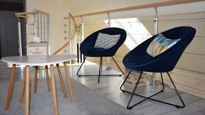 A modern room with a round table, two blue chairs, a white wall, and a wooden floor.