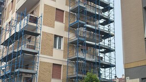 Een meerlaags gebouw met blauwe steigers, wat duidt op lopende werkzaamheden of renovatie.