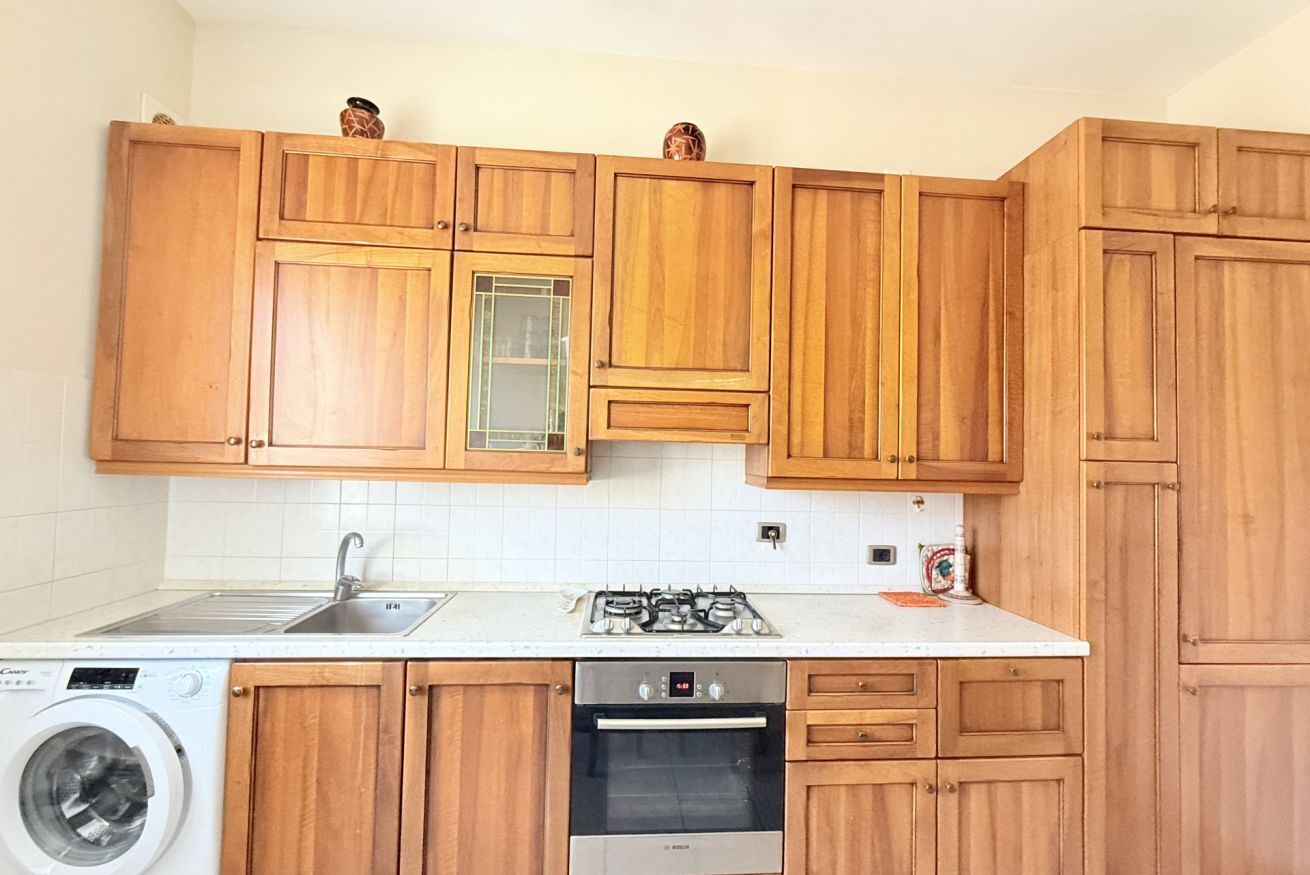 A kitchen with wooden cabinets, a washing machine, a gas stove, and an oven.