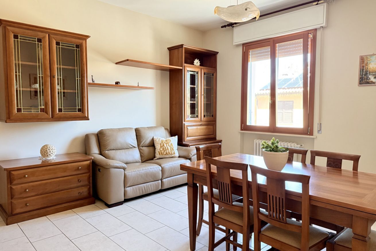 A living room with a sofa, wooden cabinet, dining table, and chairs.