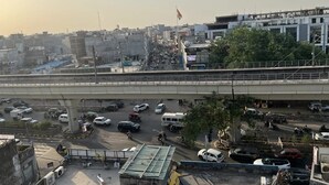A busy urban street scene with a bridge, vehicles, and buildings. - Hotel Prime Stay (New Delhi)
