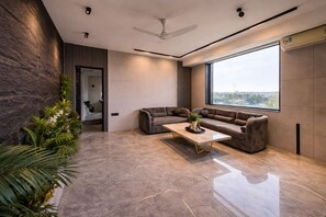 A modern living room with a large window, a ceiling fan, and a marble floor. - The Luxury Penthouse IGI Airport Delhi (New Delhi)