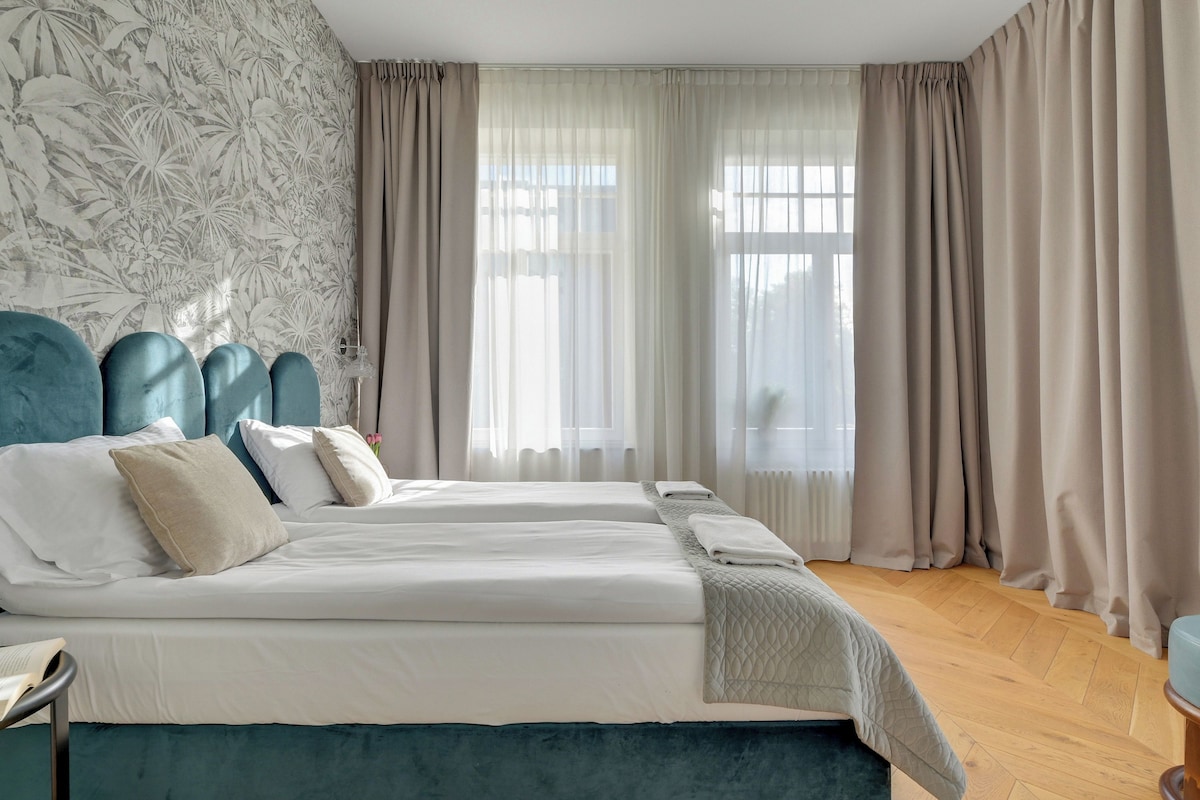 Une chambre d’hôtel avec un grand lit, une table de chevet et une vue sur la ville grâce à de grandes fenêtres.