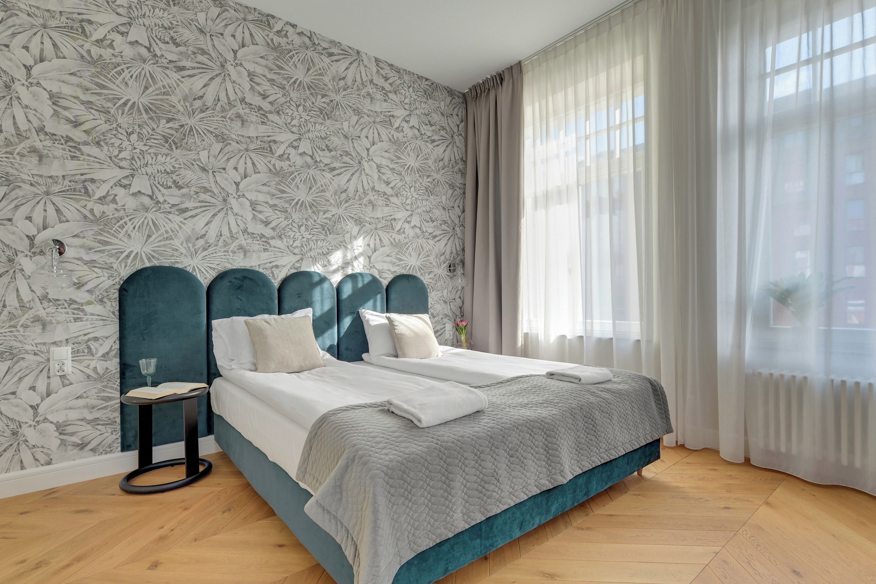 A bedroom with a bed, a nightstand, and a window with curtains.