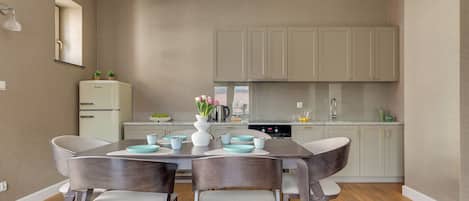 Una cocina moderna con una mesa de comedor, sillas y un refrigerador.