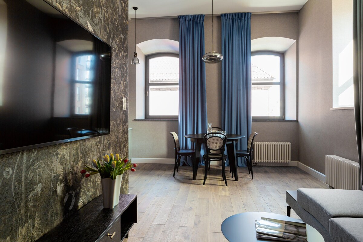 Ein modernes Wohnzimmer mit Flachbildfernseher, Esstisch mit Stühlen, Sofa und Heizkörper.