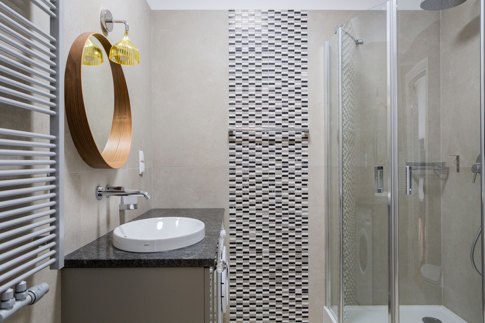 Ein modernes Badezimmer mit einem weißen Waschbecken, einer Duschkabine aus Glas und einer Wand mit Muster.