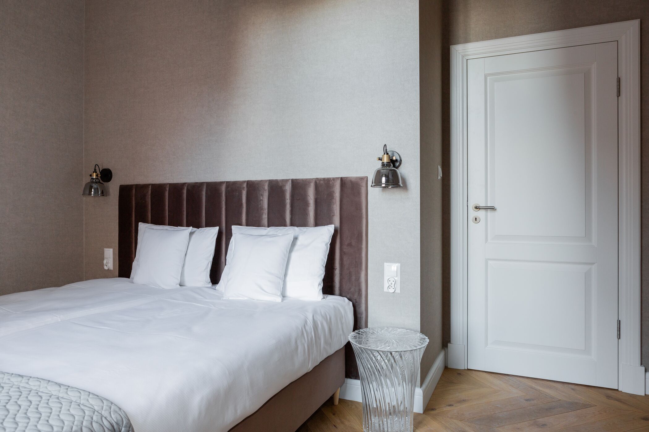 Une chambre à coucher avec un lit, une porte et une lampe fixée au mur.