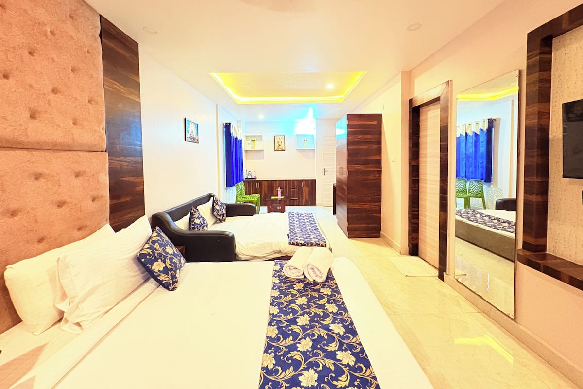 A hotel room with a large bed, a desk, a mirror, and a view of the outside.