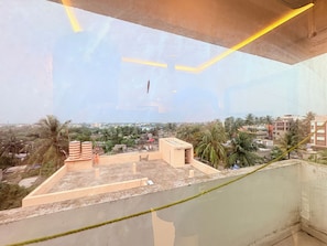 A high-rise building with a rooftop terrace featuring a small structure and a flag. - Rohit Rohini Swami Pranavananda Marg (Puri)