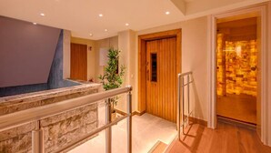 A hotel lobby with a stone wall, a wooden door, and a staircase with metal railings. - 2 Person Holiday Park Home in Erlbach (Markneukirchen)