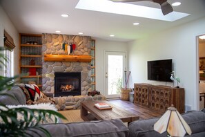 A living room with a stone fireplace, a television, and a sofa. - Creekside Cabin Walking Distance to Lake Michigan (South Haven)