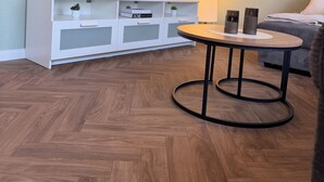 Ein Wohnzimmer mit Fernseher, weißem Unterhaltungsschrank, rundem Couchtisch und einer Couch.