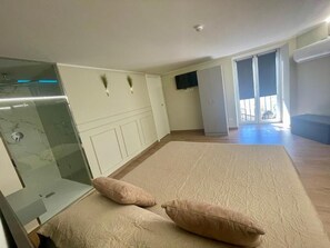 Ein geräumiges Zimmer mit einem großen Bett, einer Duschkabine aus Glas, einem Fernseher und einem Balkon mit Aussicht.