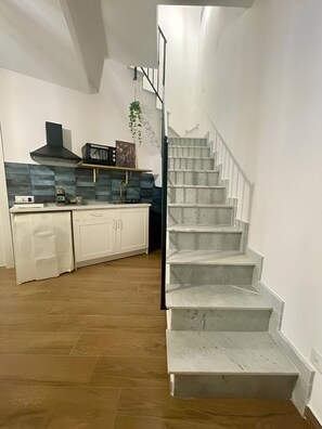 Eine moderne Küche mit weißen Schränken, einer schwarzen Dunstabzugshaube und einer blau gefliesten Spritzschutzwand.