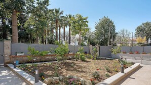 A garden with a paved walkway, a low wall, and various plants. - Villa Cappuccini – Lower Floor Apartment with Shared Terrace, Wi-Fi & Air Conditioning (Sant'Agnello)