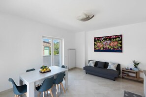 Un salon moderne comprenant un coin repas, un canapé gris, un radiateur et un grand tableau floral accroché au mur.